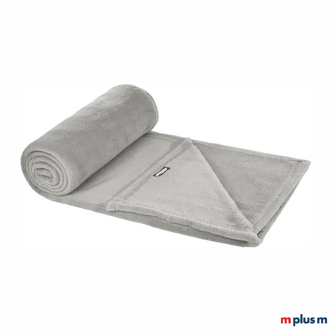 Die hellgraue Decke 'Flauschi' wird mit Logo Stick ein idealer Werbeartikel, der sich perfekt für kältere Tage eignet.